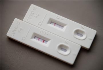 Ein positiver Corona-Schnelltest (l) liegt auf einem Tisch neben einem Corona-Schnelltest, der schwach eine positive Linie hat.