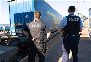 Zwei Polizisten stehen am Bahngleis vor einem Güterzug