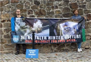 Tierschutzaktivisten stehen mit einem Transparent mit der Aufschrift "Tierquäler hinter Gitter! Gerechtigkeit für ihre Opfer." vor dem Amtsgericht.