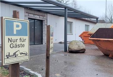 Vor einem Gebäude stehen Bauschuttcontainer. Ein Schild weist darauf hin, dass das Parken nur für Gäste erlaubt ist.