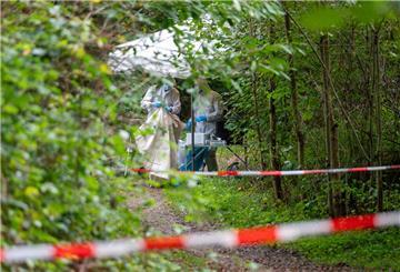 Mitarbeiter der Spurensicherung stehen auf einem abgesperrten Waldweg.