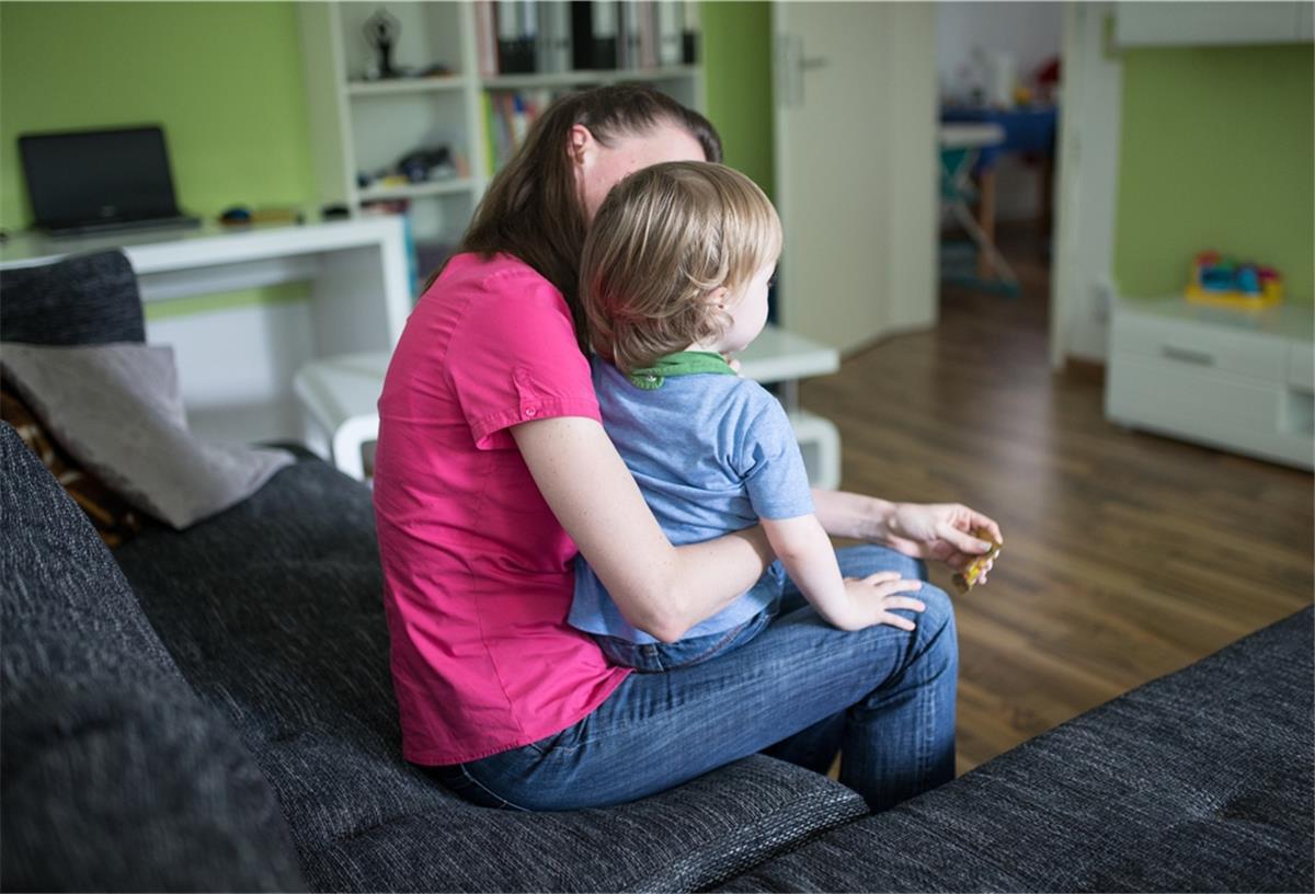 Land Bremen: Neue Beschlüsse gelten nicht für Kinder Eine Mutter sitzt mit ihrem Sohn auf dem Schoß auf einer Couch.
