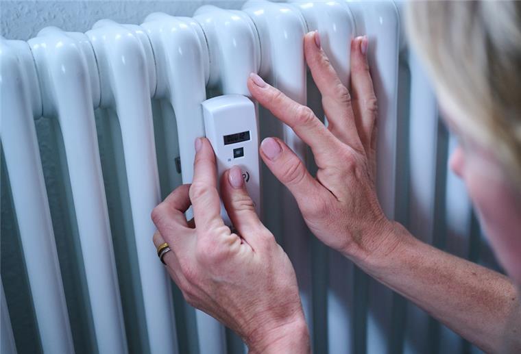 Energiepreisbremsen sollen rückwirkend ab Januar gelten Eine Frau kontrolliert einen Heizkostenverteiler an der Heizung