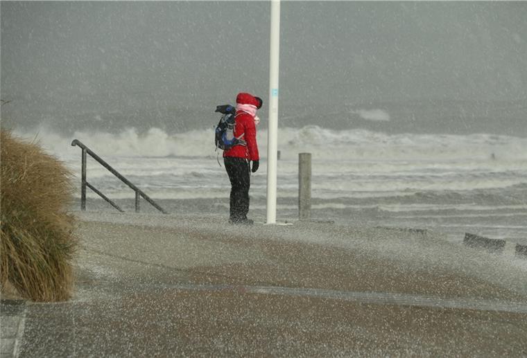 Den Norden erwartet ein stürmisches Wochenende Eine Spaziergängerin blickt auf Norderney auf den Nordstrand und die Wellen der vom Sturm aufgepeitschten Nordsee