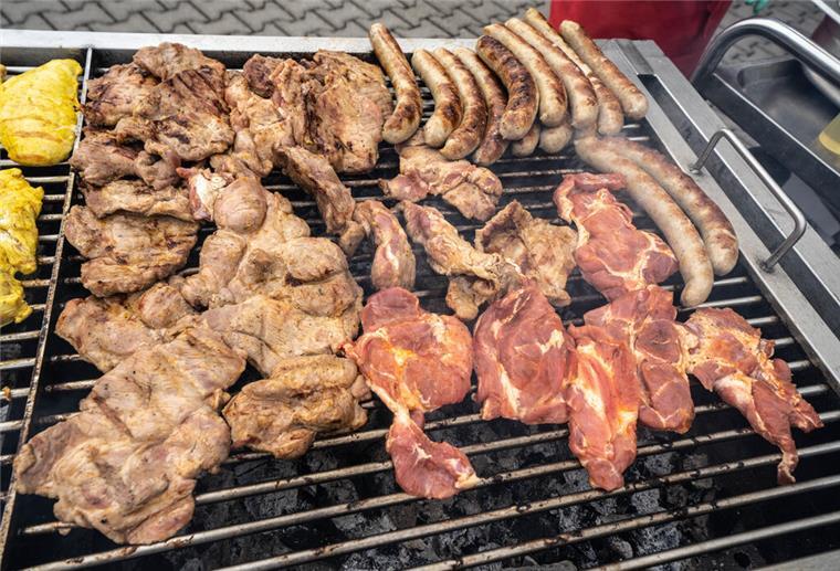 Sommerzeit, Grillzeit: Neue Fleischkennzeichnung kommt auf die Verpackungen Zahlreiche Fleischstücke und Würste liegen auf einem großen Holzkohlegrill.