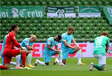 Im Weserstadion: Spieler aus Bremen und Wolfsburg knien gemeinsam auf dem Rasen am Mittelkreis, um ein Zeichen gegen Rassismus zu setzen.