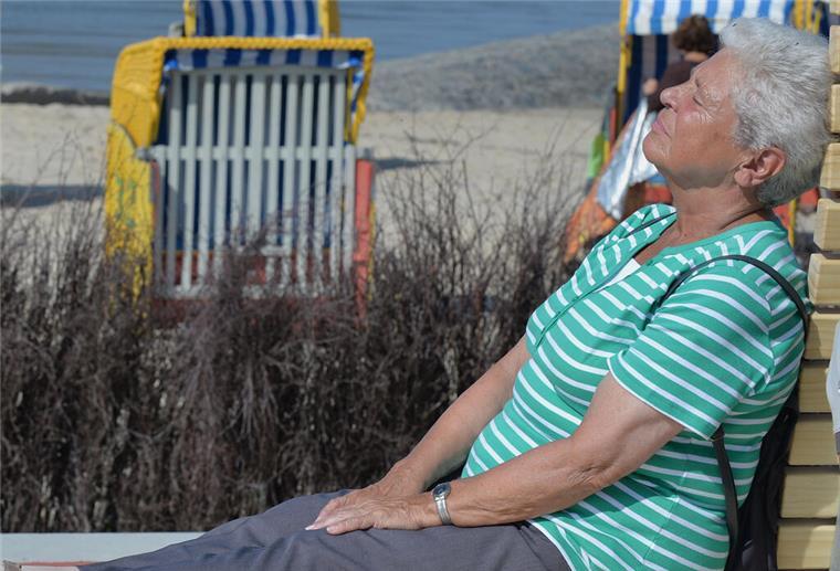 Rente im Ausland: Das müssen Rentner über Steuern und Auszahlung wissen Eine ältere Frau sitzt an einem Strand.