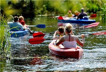 Acht Ausflügler sind in drei Kanus auf einem Fluss unterwegs