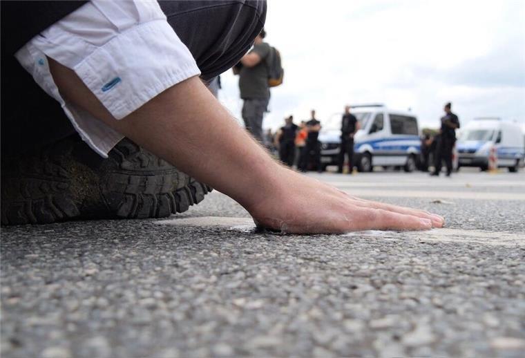 Müssen Klimakleber künftig für Einsätze in Bremen zahlen? Ein Klimaaktivist hat sich mit der Handfläche am Asphalt einer Straße in der Bremer Innenstadt festgeklebt