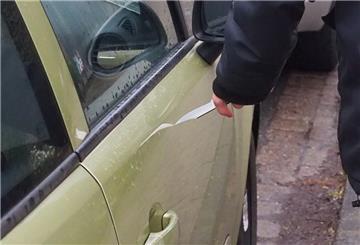 Ein Mann zerkratzt ein Auto mit einem Messer.