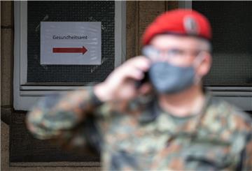 Ein Bundeswehr-Soldat telefoniert mit Mundschutz vor einem Gesundheitsamt. 
