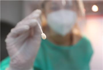 Eine medizinische Assistentin nimmt in einer Teststation mit einem Tupfer einen Abstrich für einen PCR-Test.