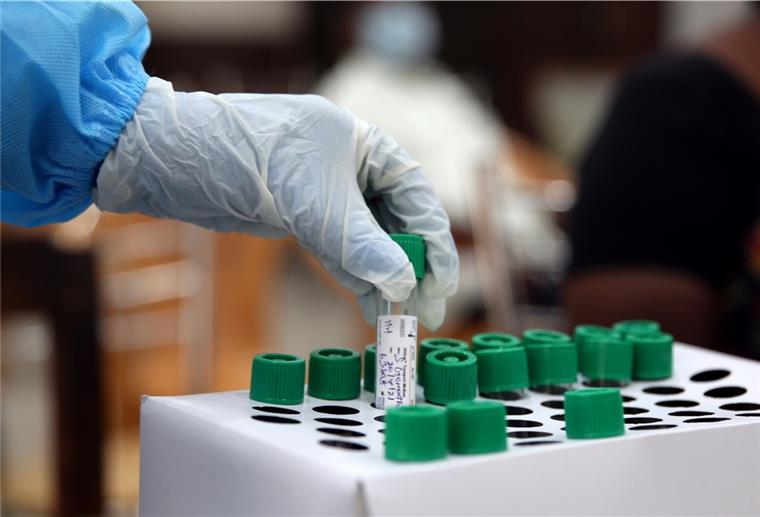 Bremerhaven und Corona: Inzidenz steigt deutlich Ein Mitarbeiter des Gesundheitswesens hält in einem Regierungsbüro in Chennai eine Probe für einen RT-PCR-Test in der Hand.