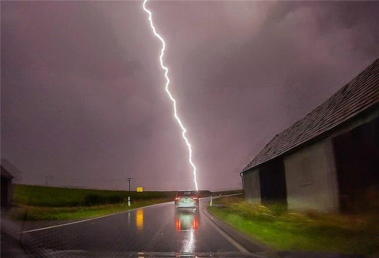 Achtung! Unwetterwarnung für Bremerhaven und umzu Ein Blitz ist am Himmel hinter einer Straße zu sehen.