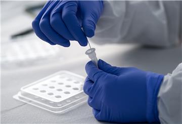 Ein Mitarbeiter der Malteser führt einen Tupfer nach einem Abstich im Rachen eines Patienten in ein Röhrchen mit der Trägerflüssigkeit für den Corona-Schnelltest. 