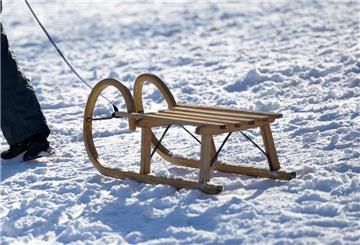 Ein Junge zieht seinen Holzschlitten in der Sonne durch den Schnee im Schanzenpark.