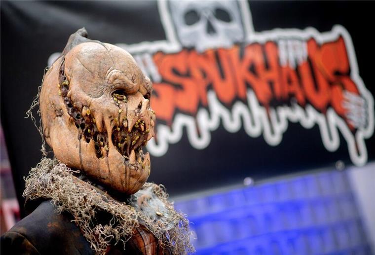 Erschrecken und Gruseln zu Halloween: Gruselhäuser in Niedersachsen Eine Figur steht im Eingangsbereich vor einem Banner der temporären Attraktion «Das Spukhaus 2023».