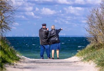 Ein Rentnerpaar steht am ansonsten menschenleeren Strand und schaut aufs Meer. In den kommenden Jahren gehen immer mehr Baby-Boomer in Rente. Experten schlagen deshalb den „Boomer-Soli“ zur Sicherung der Renten vor.