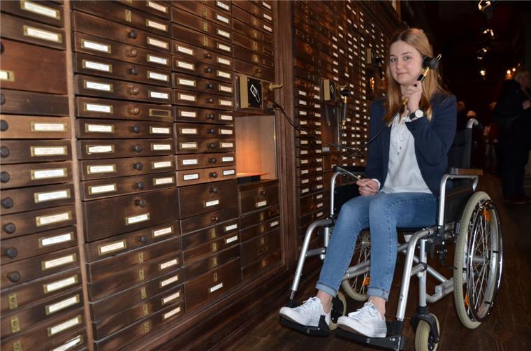 In der „Galerie der sieben Millionen“ wird an Hörstationen über Auswanderer-Biografien berichtet. Damit Rollstuhlfahrer diese nutzen können, sind einige Hörer tiefer angebracht. Fürs Foto zeigt Auswandererhaus-Mitarbeiterin Jennifer Kluge, wie das klappt.