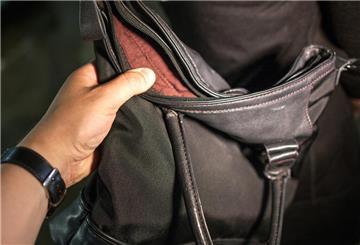  Ein Hand greift nach einer Geldbörse in einer Damenhandtasche. 