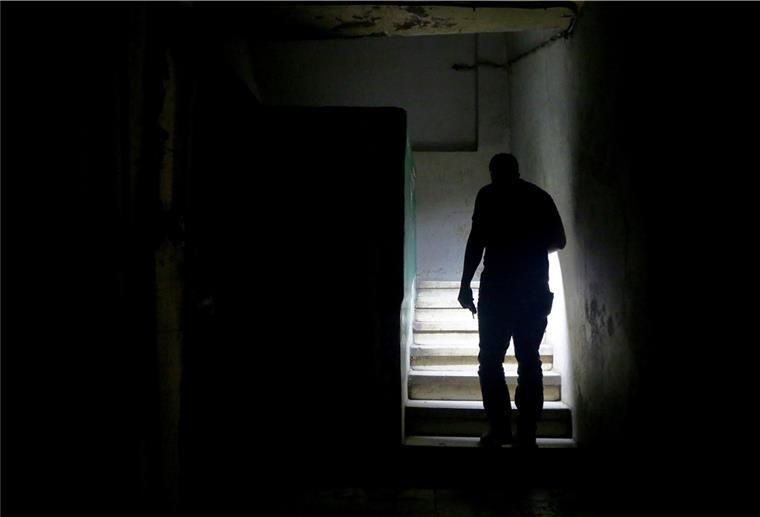 Stromausfall in Mitte und Lehe: Beschädigtes Kabel ist schuld Ein Mann geht mit Taschenlampe im Dunkeln durchs Treppenhaus.