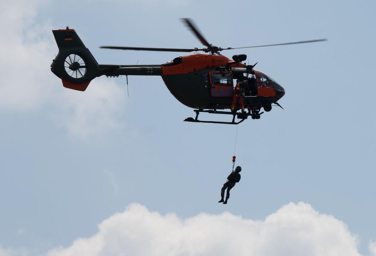 Ein Hubschrauber rettet eine Person, die an einem Seil hochgezogen wird.