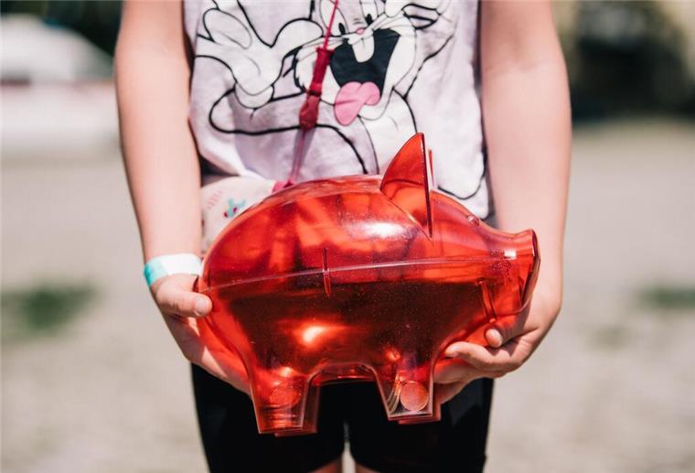 Kindergeld beantragen: Worauf Eltern jetzt unbedingt achten müssen Ein Kind hält eine rotes Sparschwein vor dem Körper. In Deutschland muss der Antrag für das Kindergeld noch aktiv gestellt werden. Wir klären die wichtigsten Fragen, die Eltern haben.
