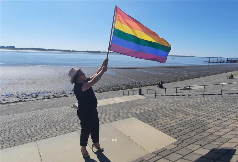 In Bremerhaven wird die Regenbogenflagge ausgepackt Eine Person hält eine Regenbogenflagge in die Luft