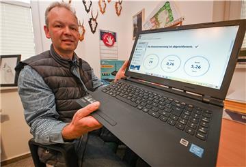 Ein Mann hält seinen Laptop in die Kamera.