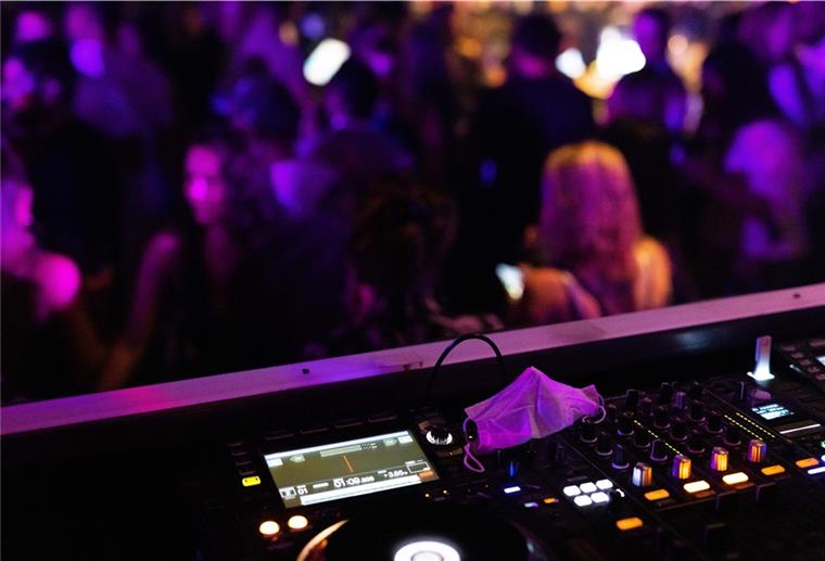 Corona in Münster: 83 Infizierte nach 2G-Party Eine Maske liegt auf dem Mischpult, vor dem Menschen tanzen