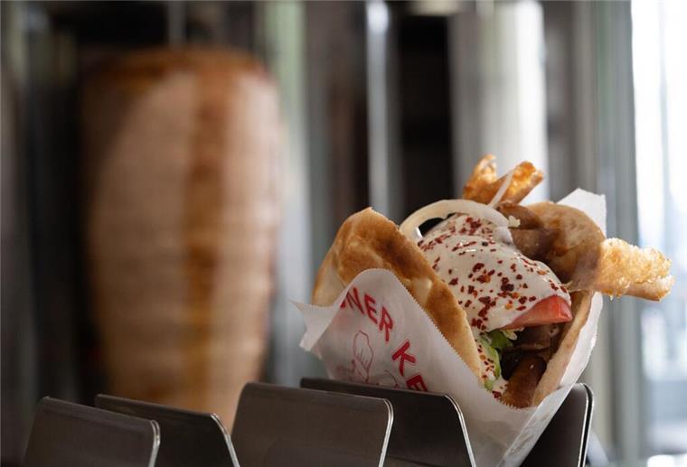 Ein Döner ist vor einem Dönerspieß sehen.