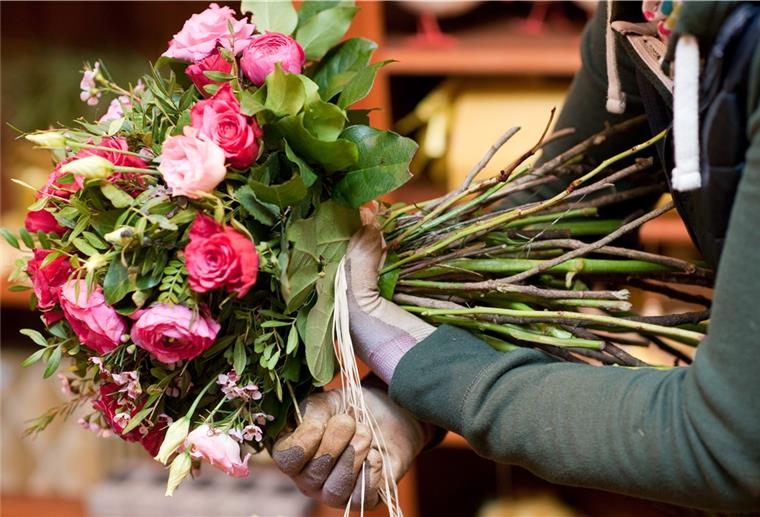 Niedersachsen öffnet Blumenläden Floristin mit Blumenstrauß in der Hand.