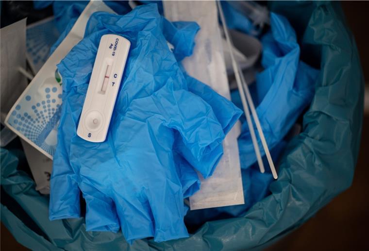 Ein negativer Covid-Schnelltest liegt auf einem medizinischen Handschuh in einer Teststelle im Mülleimer.