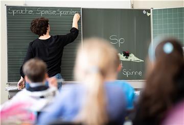 Eine Lehrerin schreibt in einer Grundschule Wörter auf eine Tafel.