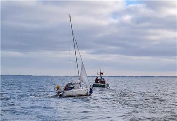 Ein Schiff der Seenotrettung geleitet in Segelboot in den sicheren Hafen.