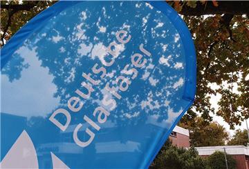 Werbebanner der Deutsche Glasfaser vor einem Baum und einem Gebäude.