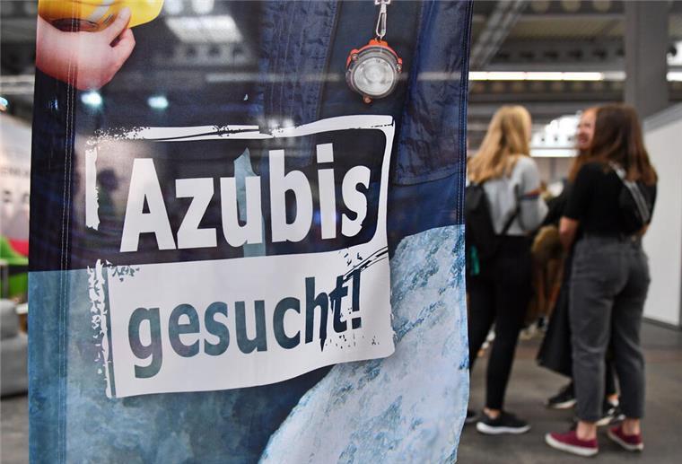 Das Schild Azubis gesucht steht auf einer Messe.