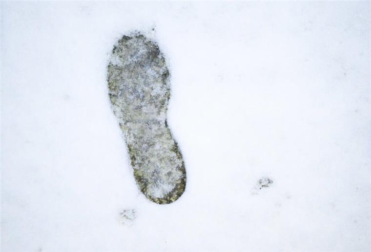  Ein einzelner Fußabdruck zeichnet sich in der nassen Schneedecke ab. 