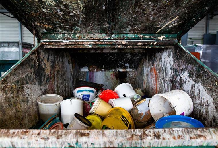 Müll-Irrtum aufgeklärt! In diesen Abfall gehören alte Farbe und Lacke wirklich Alte Farbeimer liegen in einem Container auf dem Gelände eines Recyclinghofs. In welchen Müll gehören alte Farbreste? Darf man sie im Restmüll entsorgen oder gehören sie auf den Wertstoffhof. Die Antwort überrascht.