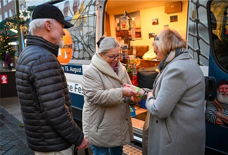 Weihnachtsmarkt: Wird nach Impfnachweisen gefragt? Ingrid Gottschalk (Mitte) verteilt nach Kontrolle des Impfnachweises die Armbänder an die Bremerhavener Christa und Jörg Fischoeder.