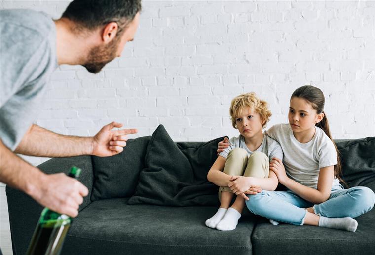 Sucht: Die Kinder leiden mit Vater vor Kindern mit Alkoholflasche in der Hand