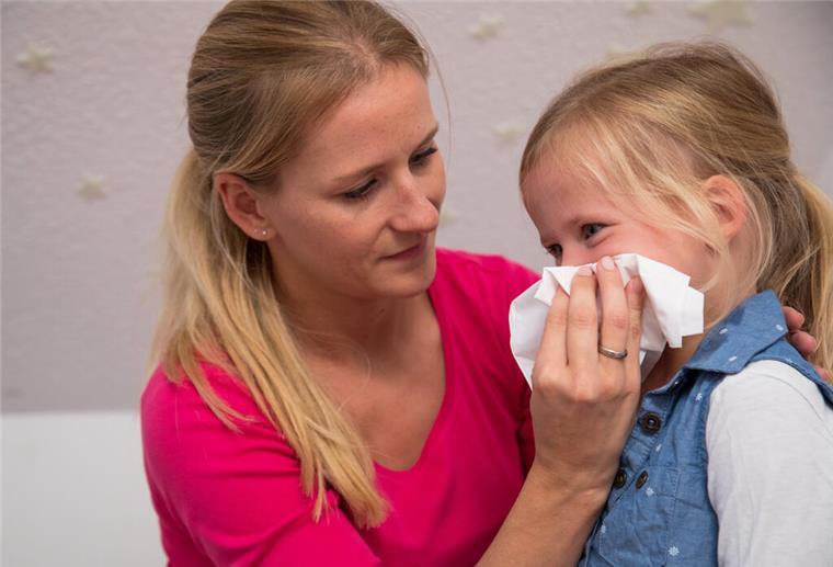 Kind krank? Unter diesen Voraussetzungen haben Eltern Anspruch auf Kinderkrankengeld Eine Frau putzt einem Kind die Nase. Wenn das Kind krank ist, gibt es oft Anspruch auf Kinderkrankengeld.