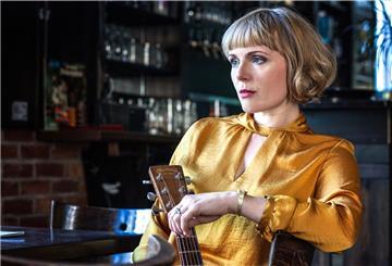 Frau mit Gitarre an einem Kneipentisch.