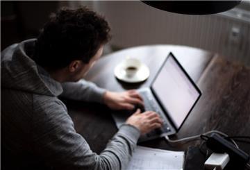  Ein Mann sitzt im Homeoffice am Tisch an einem Laptop und arbeitet. 