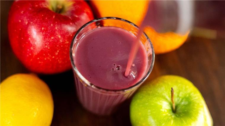 Jemand gießt roten Smoothie in ein Glas.