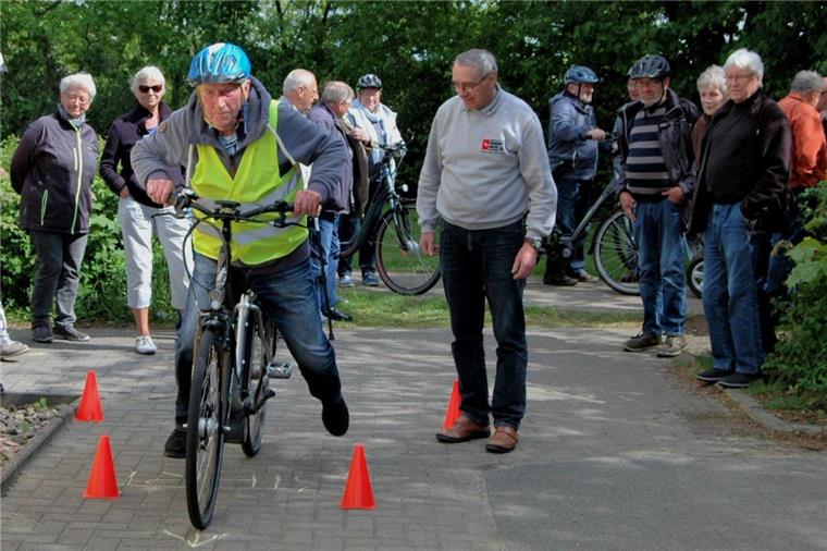 Pedelec-Fahrer in Zeven üben sich in Langsamkeit Johannes Viebrock aus Weertzen startet in den Pedelec-Parcours, Willi Scheibler von der Verkehrswacht und die weiteren Gäste des Seniorenbeirates schauen interessiert zu.