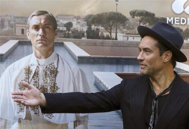 Papst aus den USA? In Serie mit Jude Law durchexerziert Jude Law vor einem Plakat mit sich als Papst Pius XIII. in der Serie „The Young Pope“. (Archivbild)