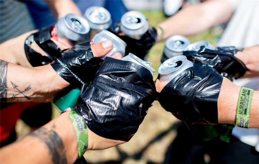 Junge Festivalbesucher stoßen auf dem Zeltplatz des Hurricane Festivals mit Dose...