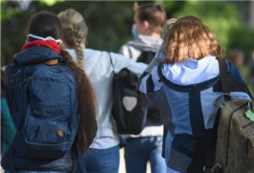 Hessen, Frankfurt/Main: Schülerinnen und Schüler eines Gymnasiums gehen vor dem Schulgebäude und tragen dabei Masken. 