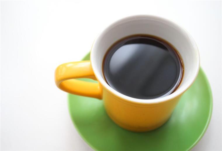 Bis zu 20 Euro pro Kilogramm Kaffee! Supermärkte führen neue Regel ein Eine gelbe Tasse mit schwarzem Kaffee steht auf einem Tisch.